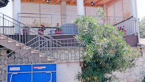 A covered outdoor area with a wooden ceiling, metal railing, and potted plants.