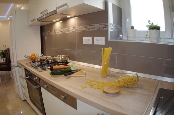 Une cuisine moderne équipée d’une cuisinière, d’une planche à découper, de légumes et de pâtes.