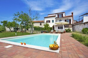 Une piscine avec un mur en pierre et un bâtiment blanc en arrière-plan.