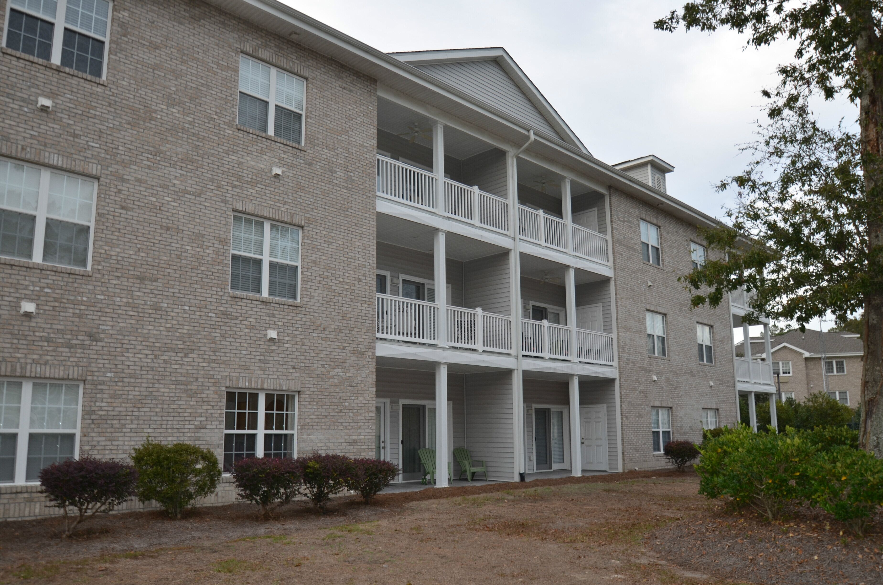 A multi-story brick building with a central balcony and a covered entrance.