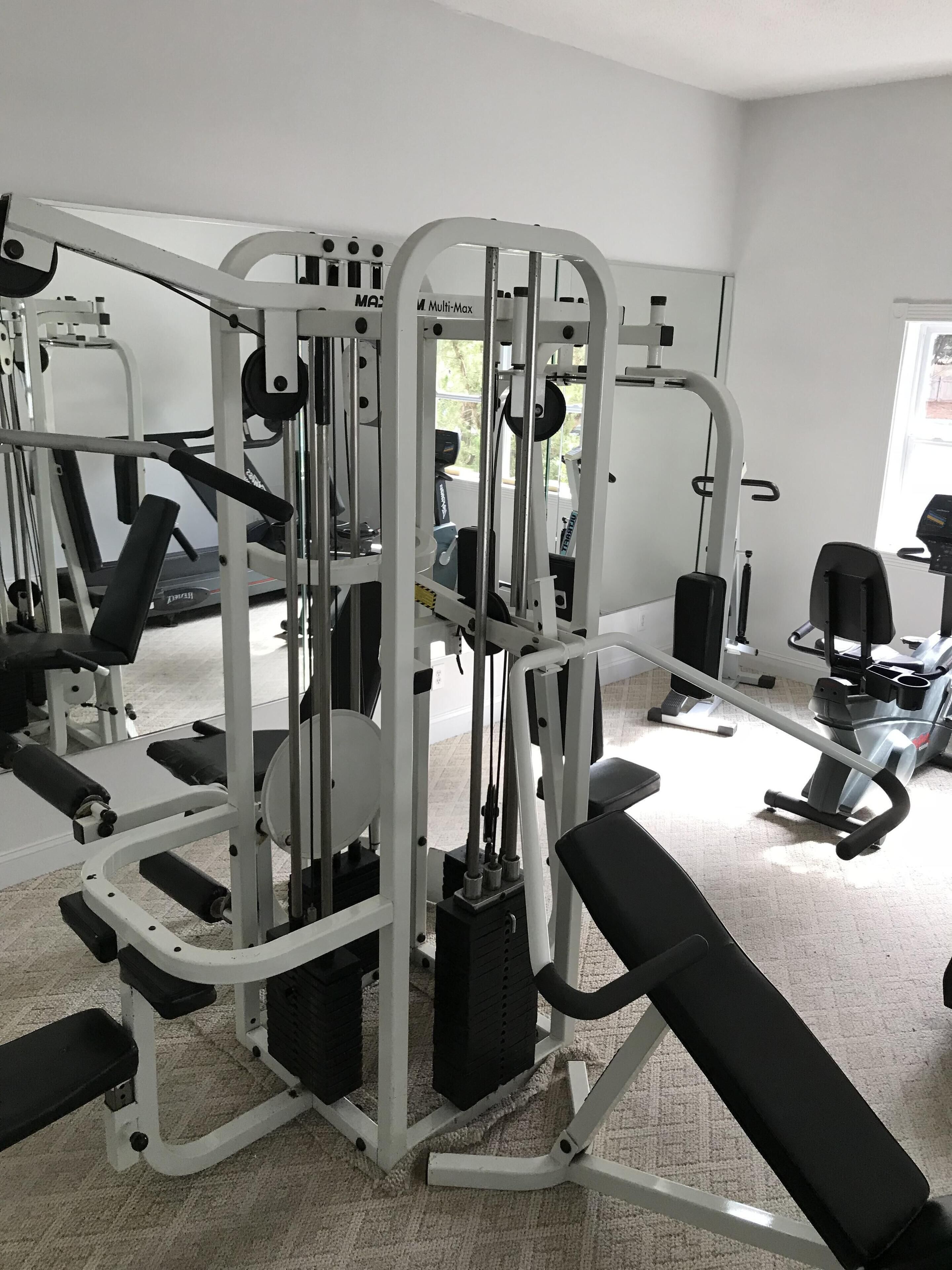 Ein Fitnessraum mit verschiedenen Trainingsgeräten, einer Bank und einem Spiegel.