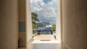 A corridor leading to a pool area with a large cruise ship in the background. - 5 Star Luxury Condo with Awesome Ocean View!  (Cozumel)