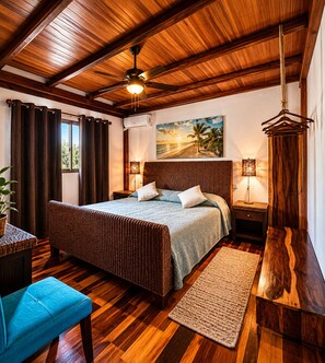 Ein Schlafzimmer mit Holzbalkendecke, einem Bett mit Kopfteil, einem Nachttisch, einer Lampe, einem Sessel und Blick ins Freie.
