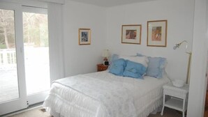 Een slaapkamer met een bed, nachtkastje, lamp en drie ingelijste foto’s aan de muur.