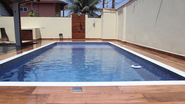 Une piscine rectangulaire entourée d’une terrasse en bois.