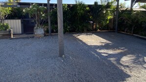 A covered outdoor area with gravel ground, wooden structures, and various plants. - Murchison Waters Accommodation (Kalbarri)