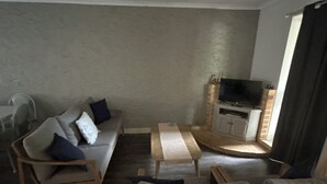A living room with a sofa, two armchairs, a coffee table, and a TV on a stand. - Murchison Waters Accommodation (Kalbarri)