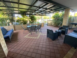A covered patio area with tiled flooring, outdoor furniture, and potted plants. - Murchison Waters Accommodation (Kalbarri)