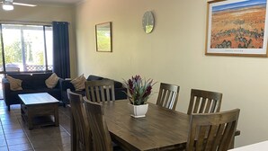 Un coin repas avec une table et des chaises en bois, une horloge et un tableau encadré au mur.