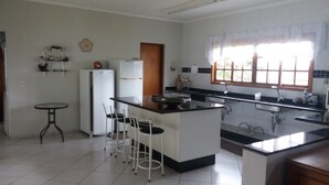 A kitchen with a central island, white cabinets, and a small dining table with chairs. - Excellent Country House (Água Preta)