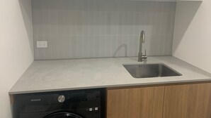 A kitchen with a built-in dishwasher, a sink, and white cabinets. - Port Willunga House on the Fleurieu Peninsula (Port Willunga)