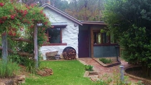 A small house with a garden, a wooden bench, and a firewood stack. - Barakee Creek - The Old Shack (Cattai)