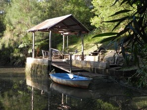 A wooden dock extending into a calm body of water, with a small boat tied to it.