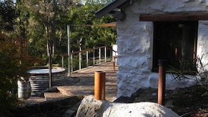 A stone pathway leading to a rustic building with a wooden deck and a hot tub. - Barakee Creek - The Old Shack (Cattai)