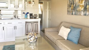 A modern kitchen with white cabinets, a coffee maker, and a glass vase on the counter.