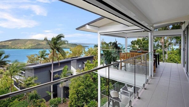 A modern glass balcony with a view of a lake and hills. - Oasis 23, Seaview Apartment on Hamilton Island (Hamilton Island)