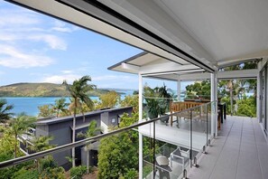 A modern glass balcony with a view of a lake and hills. - Oasis 23, Seaview Apartment on Hamilton Island (Hamilton Island)