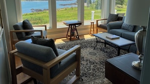 Ein Wohnzimmer mit Seeblick, ausgestattet mit einer Couch, Sesseln und einem Couchtisch.