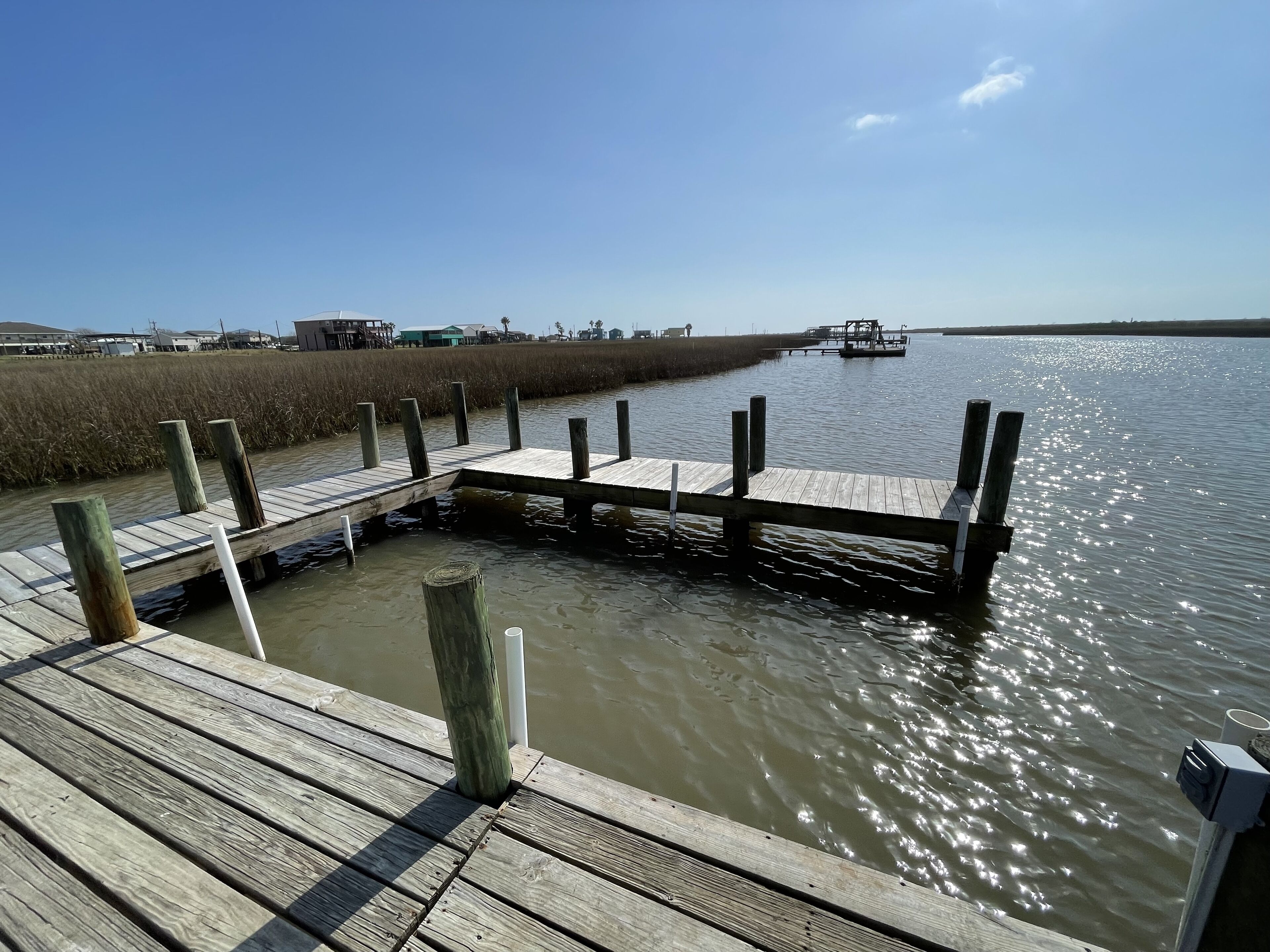 A wooden pier extending into a calm body of water with a clear sky above.