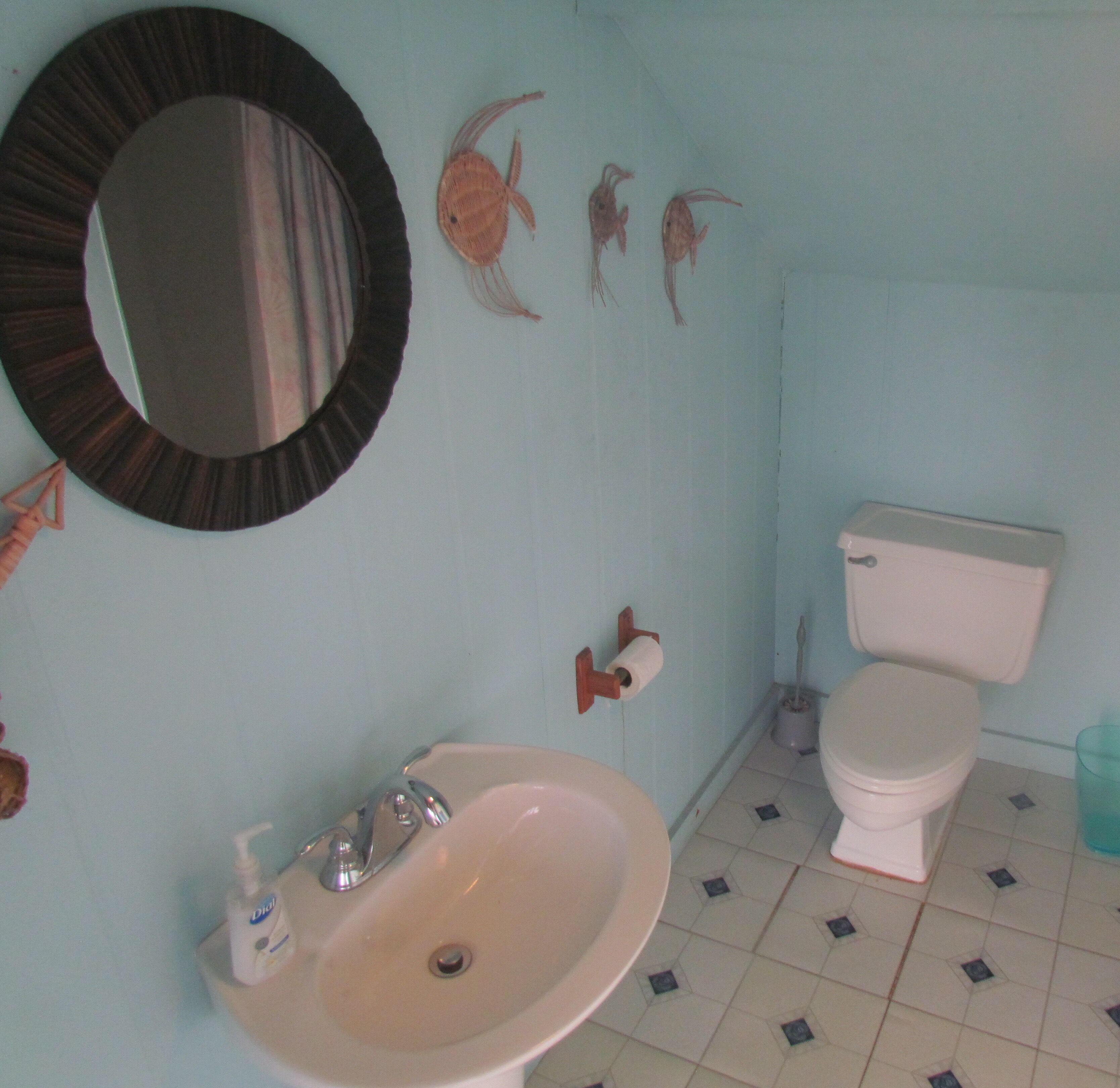 Un baño con lavamanos, inodoro y espejo.
