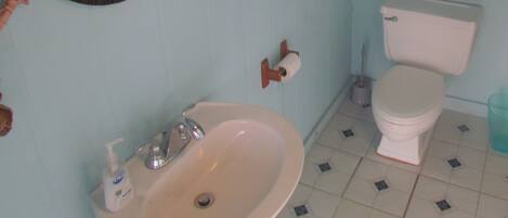 Un baño con lavamanos, inodoro y espejo.