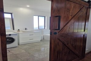 A modern bathroom with a large mirror, a sink, and a washing machine.