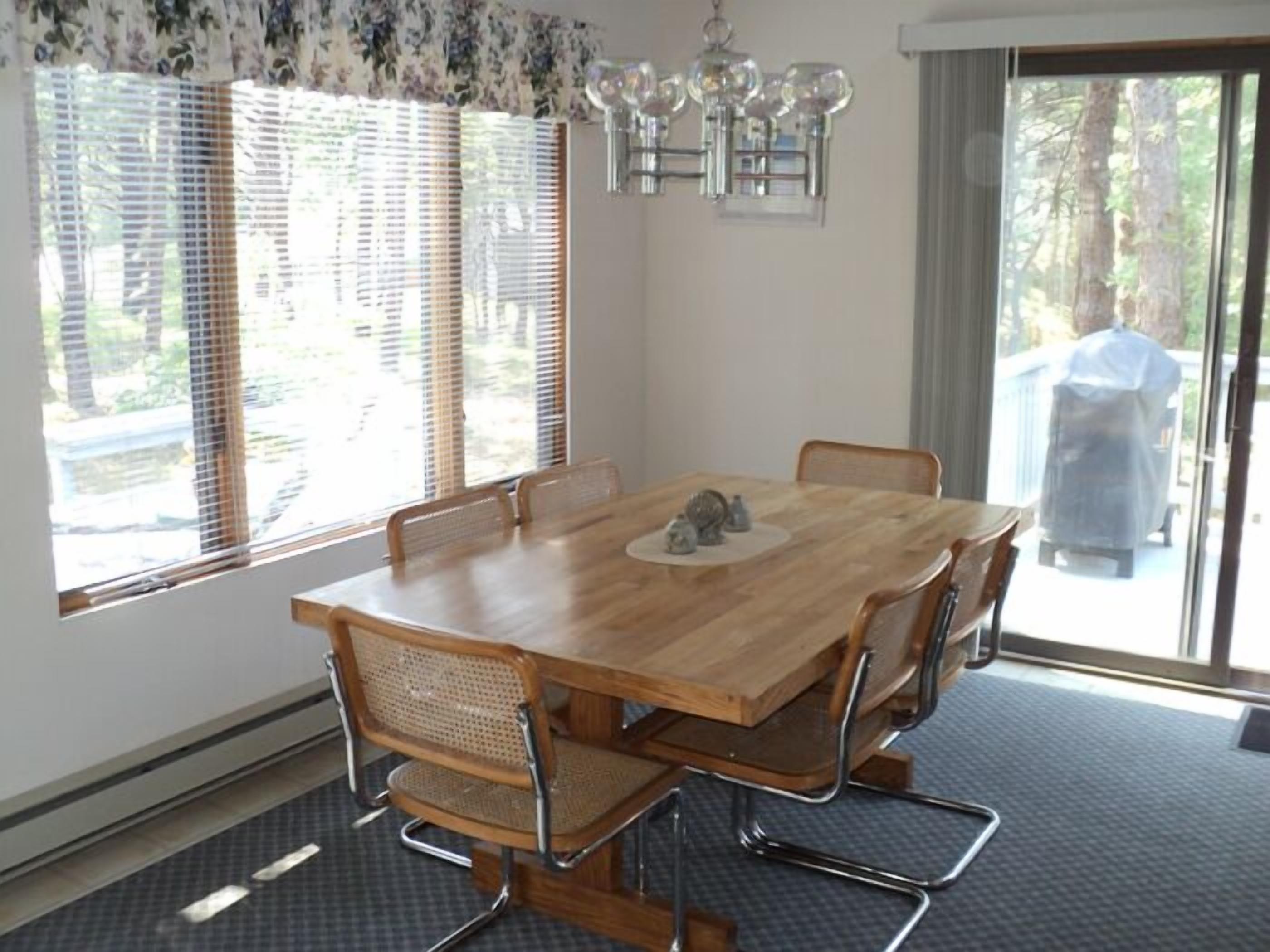 A dining area with a wooden table, six chairs, and a chandelier.