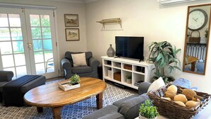 Una sala de estar con un sofá, una mesa de centro, un televisor y una estantería.