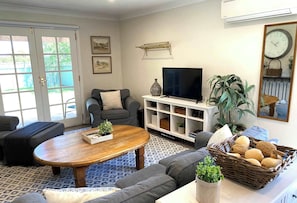 A living room with a sofa, a coffee table, a TV, and a bookshelf.