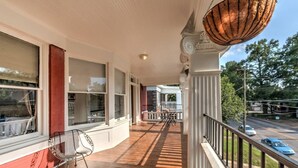 Eine überdachte Veranda mit Holzboden, weißen Geländern und einem hängenden Korb.