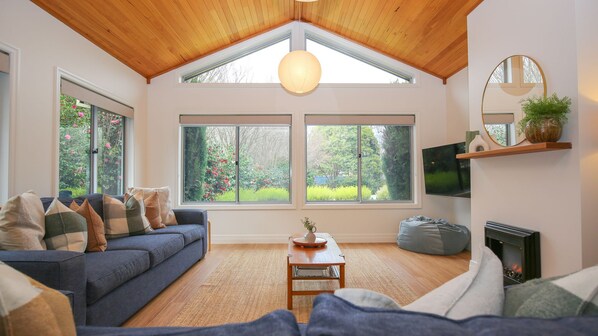 A living room with a high ceiling, a sofa, a coffee table, and a fireplace.