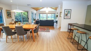 A modern kitchen with a bar area, wooden flooring, and large windows. - ON THE TRAIL : Bright (Bright)