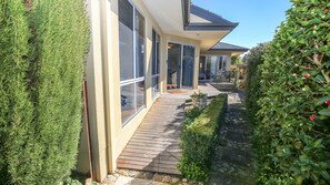 A modern house with large windows, a wooden deck, and a stone pathway. - ON THE TRAIL : Bright (Bright)
