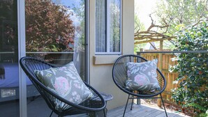 Two wicker chairs with floral cushions on a wooden deck, a glass door, and a wooden fence with greenery. - ON THE TRAIL : Bright (Bright)