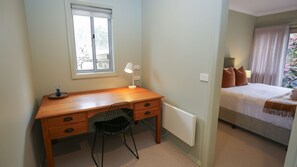 Un dormitorio con una cama, un escritorio con silla, una ventana y un radiador.