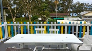 A white outdoor table with chairs, a colorful fence, and houses in the background. - Lemon Tree Shack - Family friendly by the sea (Lemon Tree Passage)