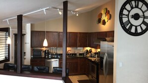 A modern kitchen with dark wooden cabinets, stainless steel appliances, and a large wall clock. - Experience a Relaxing Retreat at Lookout Mountain Lodge (30 Day Min) (Golden)