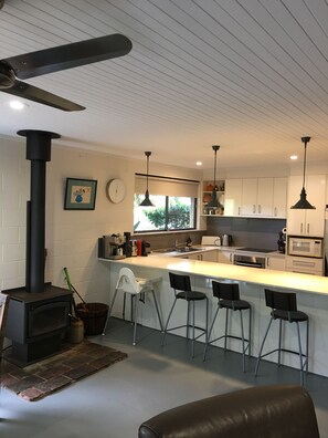 A modern kitchen with a central island, bar stools, a stove, and pendant lighting. - Corkwood at Smiths Lake - 3 bedroom pet friendly (Smiths Lake)