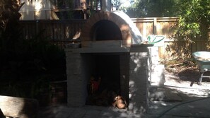 A stone-built outdoor oven with a brick archway, surrounded by a wooden fence and vegetation. - Corkwood at Smiths Lake - 3 bedroom pet friendly (Smiths Lake)