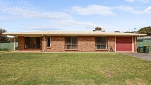 A single-story brick house with a red garage door, a covered porch, and a well-maintained lawn. - Pet Friendly in Port Elliot (Port Elliot)