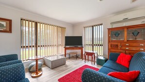 A living room with a TV, sofa, and a desk. - Pet Friendly in Port Elliot (Port Elliot)