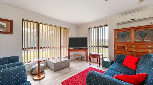Una sala de estar con televisor, sofá y escritorio.
