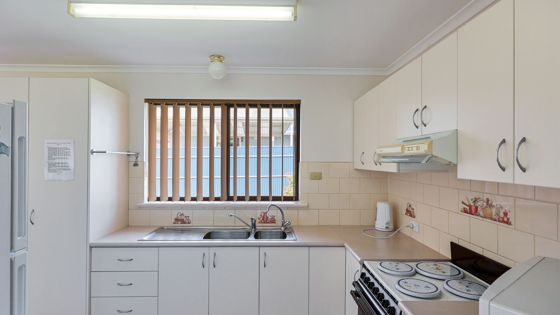 A compact kitchen with a double sink, a stove, and cabinets.