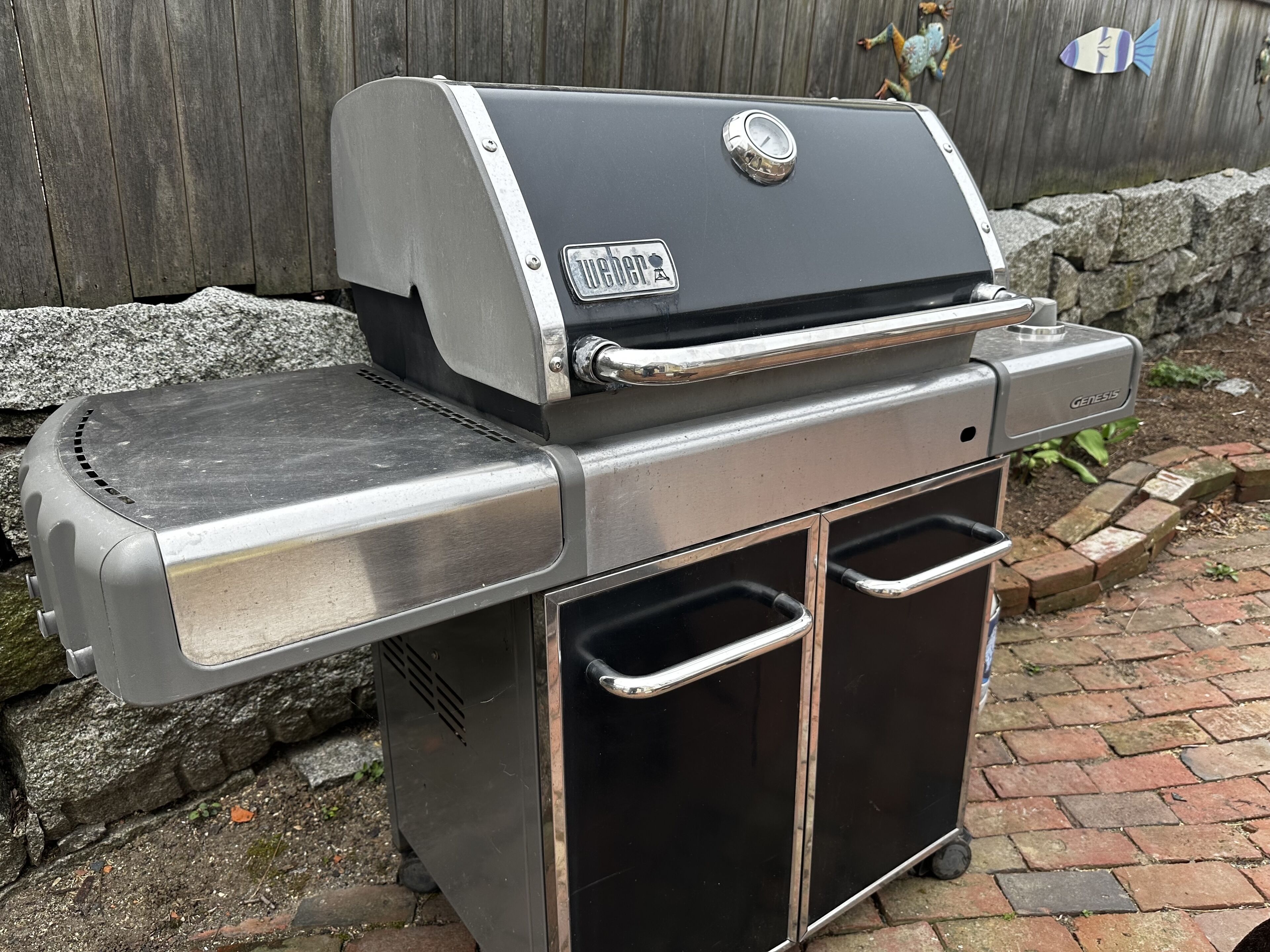 Een roestvrijstalen buitenbarbecue met een bijpassende brander en twee opbergladen.