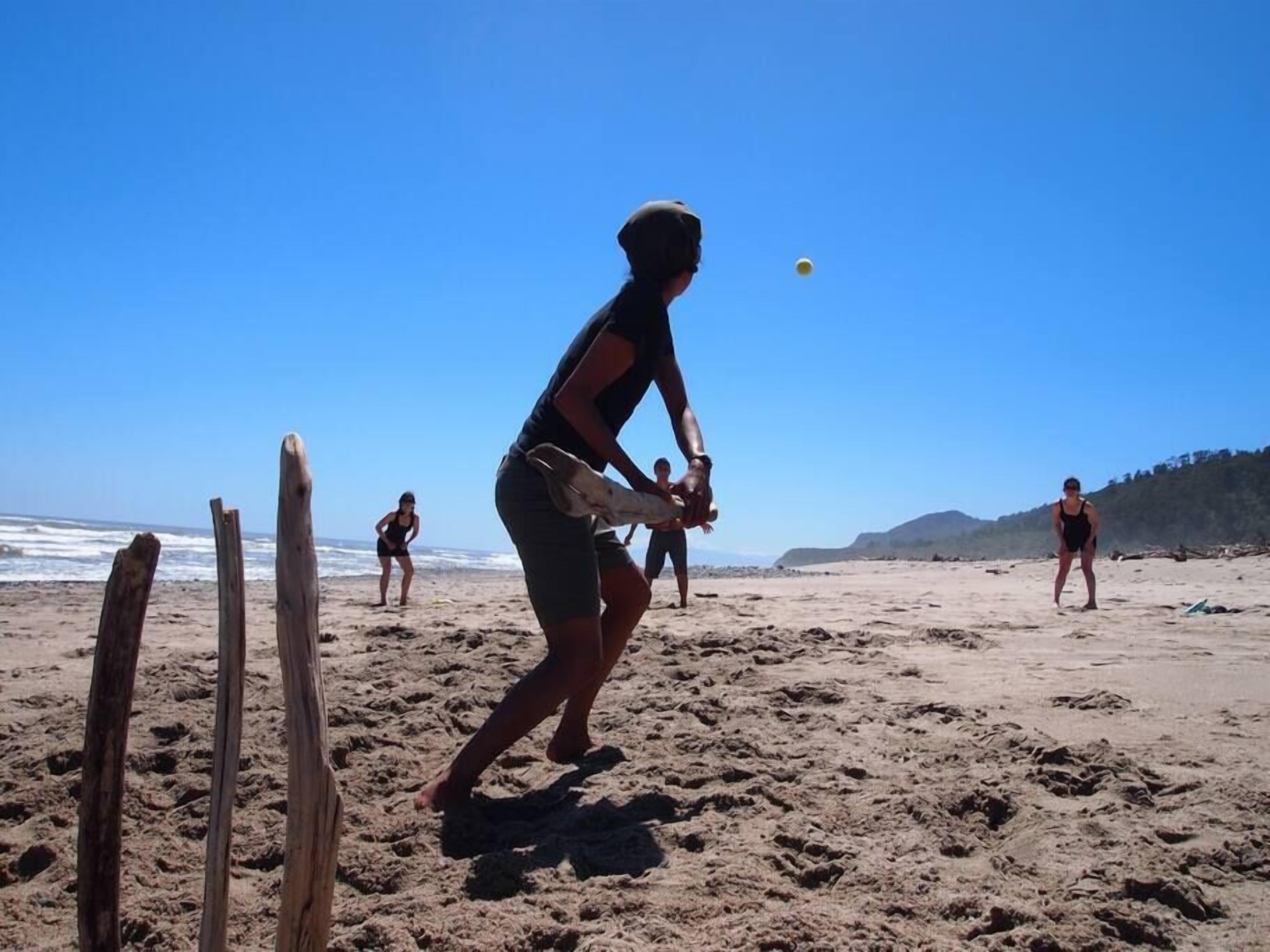 A beach volleyball game with players in sportswear and a clear blue sky.