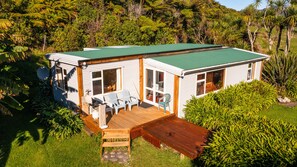 Une maison de plain-pied dotée d’un toit végétalisé, d’une terrasse en bois et d’un porche aménagé avec des sièges d’extérieur.