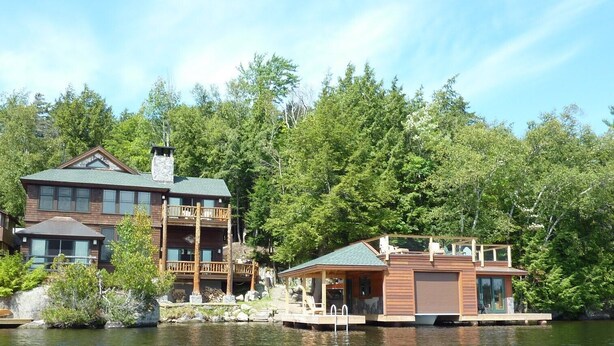 Un chalet au bord du lac comprenant un bâtiment principal, une construction en bois séparée et un quai.