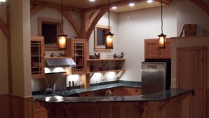 Une cuisine avec des meubles en bois, un réfrigérateur en acier inoxydable et des luminaires suspendus.