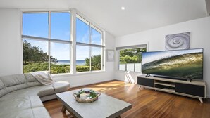 Een moderne woonkamer met een grote televisie, een bank en een salontafel met een plant.