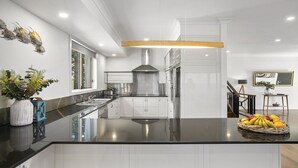 Een moderne keuken met een groot eiland, roestvrijstalen apparatuur en uitzicht op de omgeving.